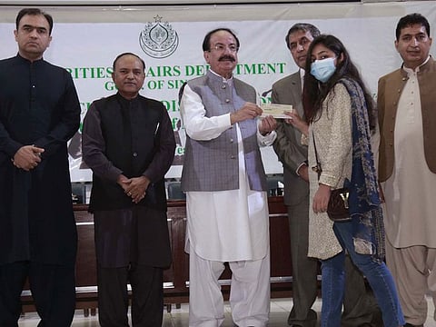 Sindh Minister for Minorities, Giyan Chand Essarani, gives a scholarship cheque to a female student from a minorty community..