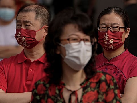 Relatives watch students entering a school for the China's national college entrance examinations, known as the gaokao, in Beijing on June 7, 2022. A rise in COVID cases have brought masks into focus to keep out coronavirus.