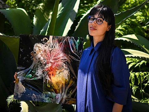 Argentinian artist Sofia Crespo holds one of her works at the Estrela garden in Lisbon.