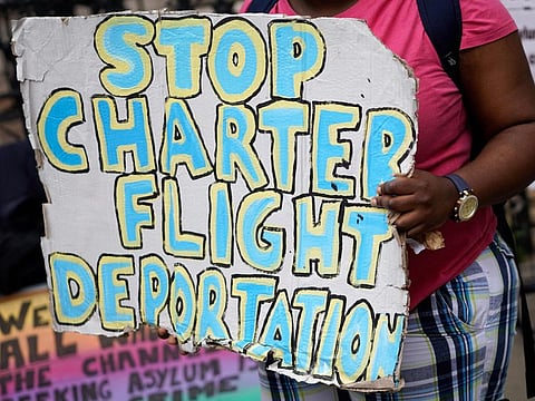 Demonstrators hold placards as they protest against Britain's plan to deport asylum seekers to Rwanda, outside the High Court in London on June 13, 2022.