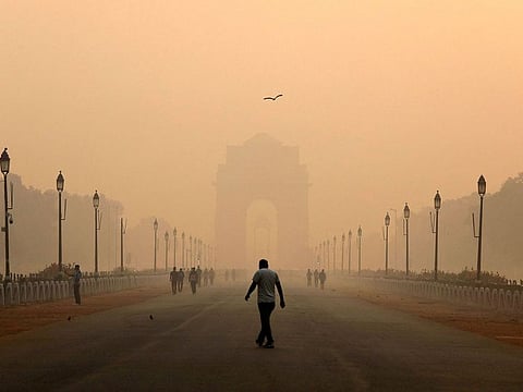 A man walks in front of the India Gate shrouded in smog in New Delhi, India.