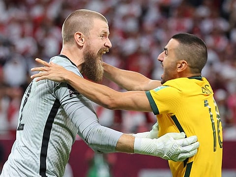 Australia's goalkeeper Andrew Redmayne (left) celebrates with defender Aziz Behich after winning the FIFA World Cup 2022 inter-confederation play-offs match against Peru at the Ahmed bin Ali Stadium in the Qatari city of Ar-Rayyan.