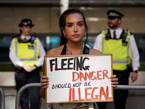A protester holds a placard as she stands outside the Home Office in central London on June 13, 2022, to demonstrate against the UK government's intention to deport asylum-seekers to Rwanda.