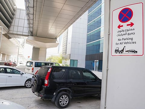 Cars park under the Dubai Metro tracks.