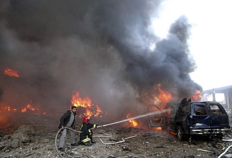 Rescue personnel hose down a burning vehicle after a bomb blast that targeted the convoy of Prime Minister Rafik Hariri in Beirut Monday, February 14 2005.