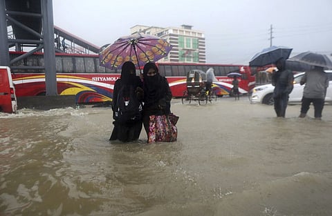 People wade through flooded waters in Sylhet, Bangladesh, on June 18, 2022.