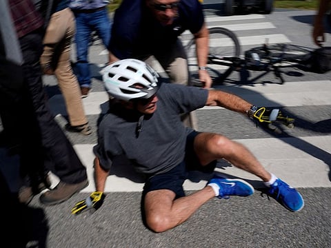 Biden falls to the ground after riding up to members of the public during a bike ride in Rehoboth Beach, Delaware, on June 18, 2022.
