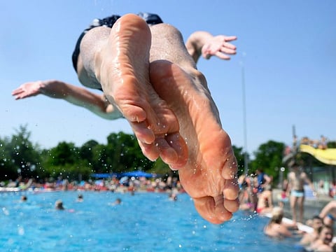 A young man jumps into the water at the Georg Arnhold pool in summer temperatures above 38 degrees Celsius, in Dresden, Germany, on June 18, 2022.