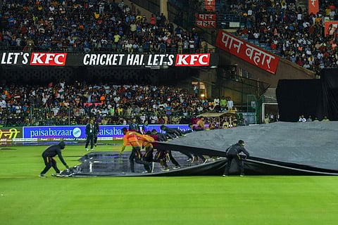 Groundsmen cover the pitch in polythene sheets as rain stops play during the fifth Twenty20 international cricket match between India and South Africa at the at the M. Chinnaswamy Stadium in Bangalore.