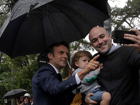 French President Emmanuel Macron poses for pictures as he leaves the polling station after voting in the second stage of French parliamentary elections at a polling station in Le Touquet, northern France on June 19, 2022.