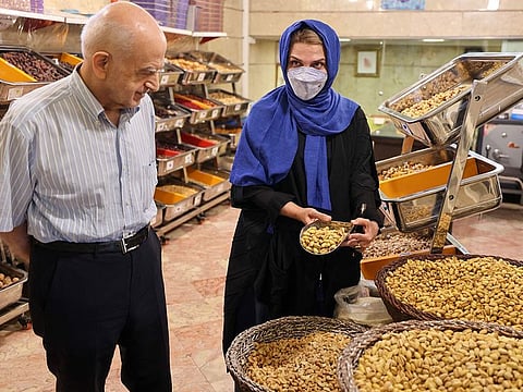 Abbas Emami (L) and his daughter Marjan display pistachios inside his shop in Tehran's famous Graz Bazaar