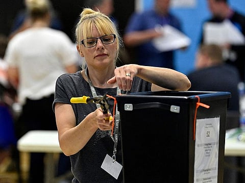 An official cuts a tie on a ballot box at the count centre in Crediton, south-west England on June 23, 2022, during the Tiverton and Honiton by-election.