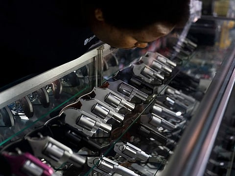 Sales associate Elsworth Andrews arranges guns on display at Burbank Ammo & Guns in Burbank, Calif., Thursday, June 23, 2022.