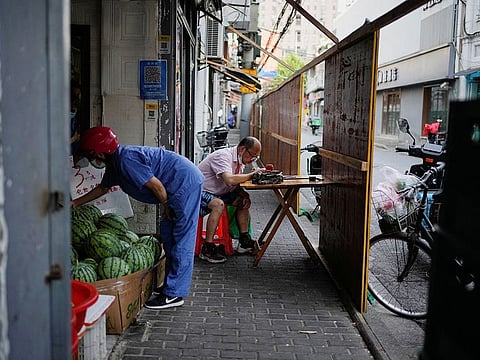 A man eats dinner behind the barrier of a residential area, amid new lockdown measures in parts of the city to curb the coronavirus disease (COVID-19) outbreak in Shanghai, China June 24, 2022.