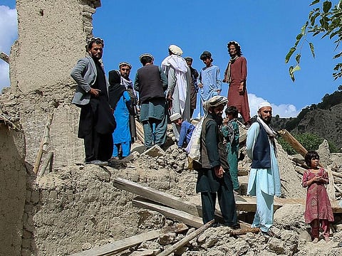 Afghan men talk amongst themselves as they look for their belongings amid the ruins of damaged houses after an earthquake in Gayan district, Paktika province, on June 24, 2022.