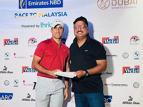 Division 2 winner Salman Karim (left) collecting his prize from Leslie Isaacs, VP of Emirates NBD.