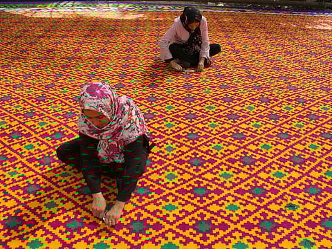 Iranian women work on weaving the largest kilim in the world in Qirokarzin, in the southern Fars province.