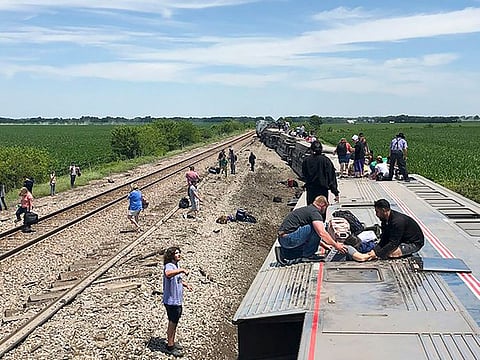 In this photo provided by Dax McDonald, an Amtrak passenger train lies on its side after derailing near Mendon, Mo., on Monday, June 27, 2022.