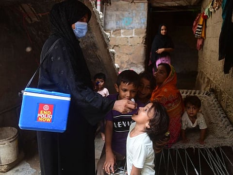 A health worker administers polio vaccine drops to a child during a door-to-door polio vaccination campaign at a slum area in Karachi on June 27, 2022.