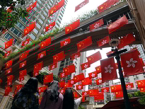 A woman takes pictures of Chinese and Hong Kong flags decorating a street, ahead of the 25th anniversary of the former British colony's handover to Chinese rule, in Hong Kong, China June 30, 2022.