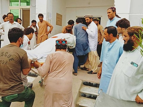 People carry the body of a passenger, who died in a bus accident, outside a hospital in Zhob district of Balochistan province on July 3, 2022.