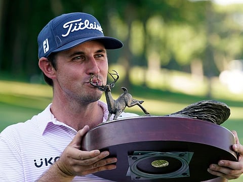 J.T. Poston kisses the trophy after winning the John Deere Classic at TPC Deere Run in Silvis on Sunday.