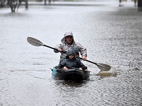 People kayak along a flooded street from the overflowing Hawkesbury river due to torrential rain in the Windsor suburb of Sydney on July 4, 2022.