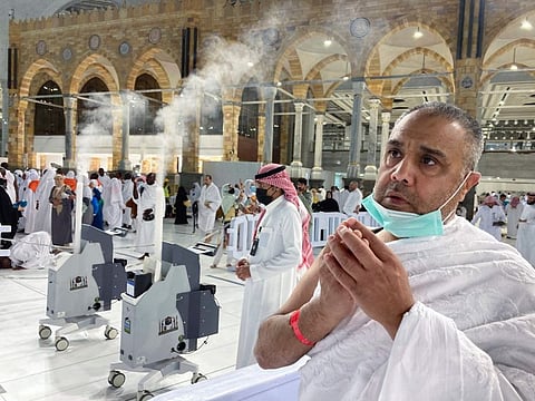 A pilgrim prays beside robots used to vacuum and sanitize air at the Grand Mosque in Mecca, on July 5, 2022.