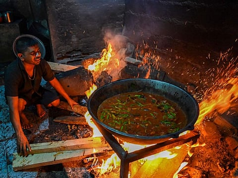 In this picture taken on March 15, 2022, a man uses firewood to cook food at a hotel in Colombo.