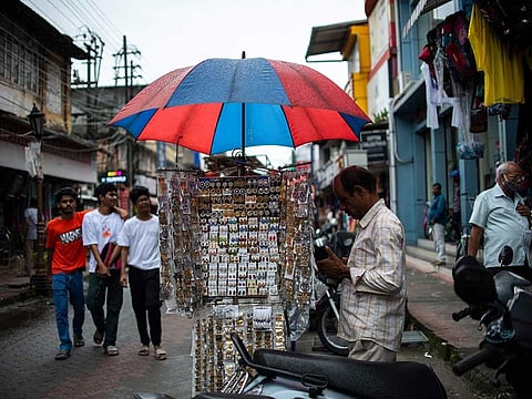 A street vendor uses an umbrella to protect himself from the rain in Kochi. Summer rains usually begin to lash coastal Kerala state around June 1 and spread across the whole country by mid-July, triggering the planting of crops such as rice, corn, cotton, soybeans and sugarcane.