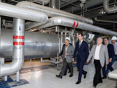 A handout picture released by the Syrian Presidency Facebook page on July 8, 2022, shows Syria's President Bashar Al Assad (C) touring a thermal power station in the eastern countryside of Aleppo province.