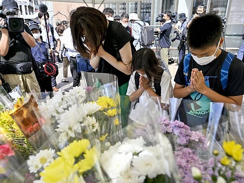 People offer prayers at a makeshift memorial near the scene where the former Prime Minister Shinzo Abe was fatally shot while delivering his speech to support the Liberal Democratic Party's candidate during an election campaign in Nara, Saturday, July 9, 2022.