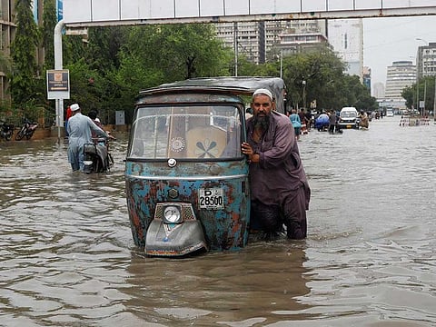 A man pushes his rickshaw (tuk tuk) through a flooded road during the monsoon season in Karachi, Pakistan July 9, 2022.