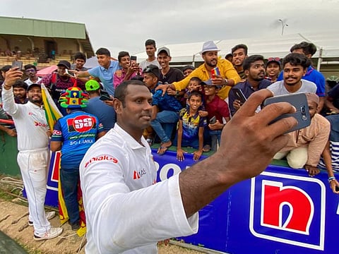 Sri Lanka's captain Dimuth Karunaratne (left) and his teammate Angelo Mathews take selfies with fans after winning the second Test against Australia in Galle on Monday.