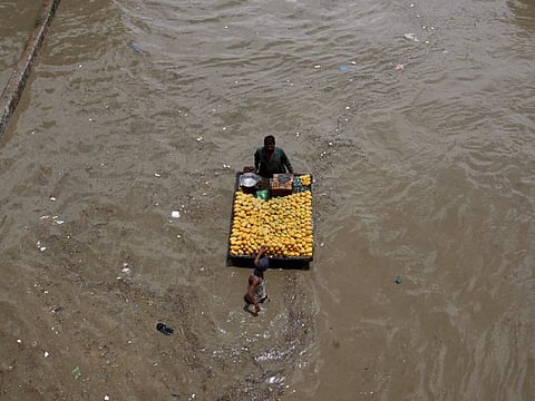 A fruit seller navigates a flooded road after a heavy rainfall in Karachi.