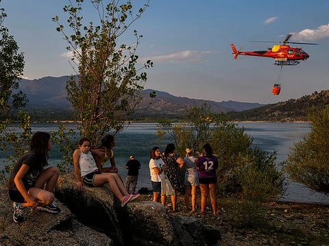A helicopter trying to extinguish a wildfire collects water from the Navacerrada reservoir, outskirts of Madrid, Tuesday, July 12, 2022.