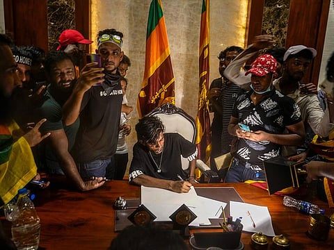 A protester sits on a chair surrounded by others after storming the Sri Lankan Prime Minister Ranil Wickremesinghe's office, demanding he resign after president Gotabaya Rajapaksa fled the country amid economic crisis in Colombo, Sri Lanka.