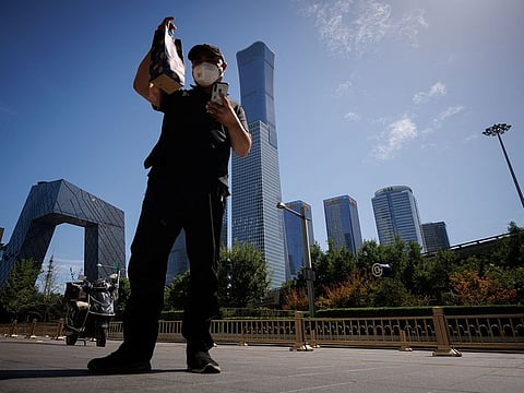 A delivery driver checks the address on a parcel outside a shopping mall the the Central Business District in Beijing, China, July 14, 2022.