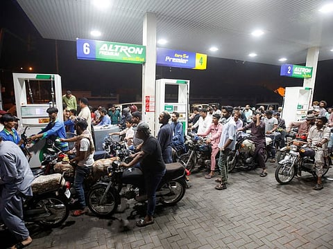 People wait their turn to get fuel at a petrol station, in Karachi in a file photo.