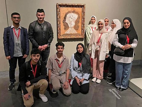 UAE University students pose in front of a Picasso painting.
