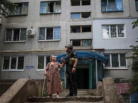 A police officer helps an elderly woman leave her flat in a residential building damaged by a Russian military strike, amid Russia's attack on Ukraine, in Kramatorsk, in Donetsk region, Ukraine July 19, 2022.