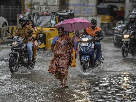 Commuters make their way along a waterlogged street during monsoon rainfall in Hyderabad on July 22, 2022.