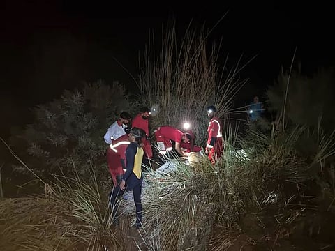 In this photo provided by the Iranian Red Crescent Society on Saturday, July 23, 2022, members of a rescue team search for missing people of Friday's flash floods in Iran's drought-stricken southern Fars province, Iran.