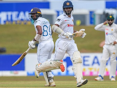 Sri Lanka's captain Dimuth Karunaratne (right) and Oshada Fernando run between the wickets during the first day of the second Test against Pakistan at the Galle International Cricket Stadium in Galle.