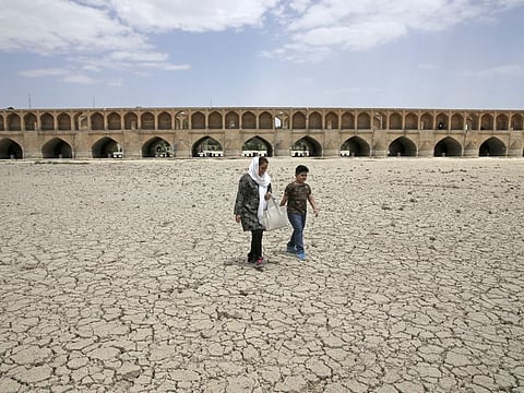 A woman and a boy walk on the dried up riverbed of the Zayandeh Roud river that no longer runs under the 400-year-old Si-o-seh Pol bridge, named for its 33 arches, in Isfahan, Iran.
