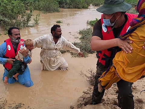 Rescue workers help villagers to evacuate them from flooded area caused by heavy rains, in Lasbella, a district in Pakistan's southwest Balochistan province on July 26, 2022.