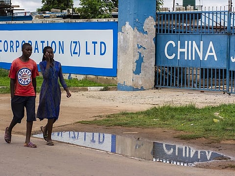 Pedestrians walk past a China Jiangxi Corporation Ltd. construction site in Lusaka, Zambia