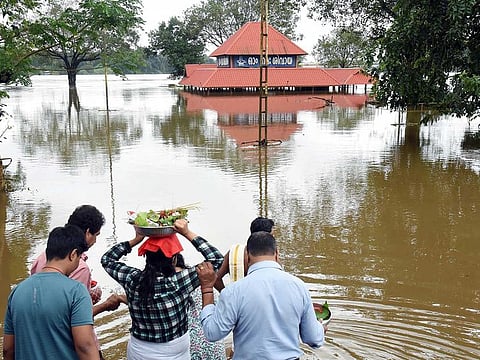 Devotees enter a partially submerged Aluva Shiva Temple after the release of dam water, leading to overflowing of Periyar River, in Kochi on Friday, August 5, 2022.