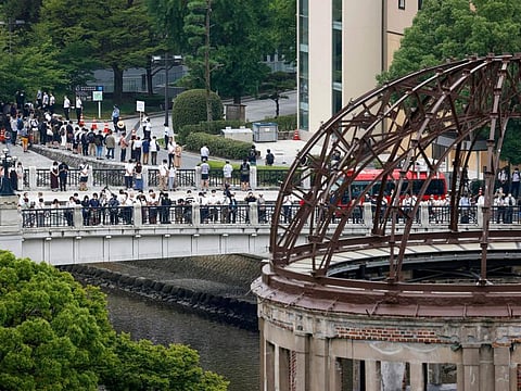 Visitors observe a minute of silence for the victims of the atomic bombing, at 8:15am, the time atomic bomb exploded over the city, at the Hiroshima Peace Memorial Park during the ceremony to mark the 77 anniversary of the bombing, in Hiroshima, western Japan Saturday, Aug. 6, 2022.