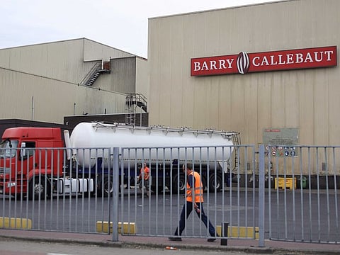 In this photograph taken on June 30, 2022, employees walk next to a vehicle inside the Barry Callebaut production site at Wieze, near Brussels.